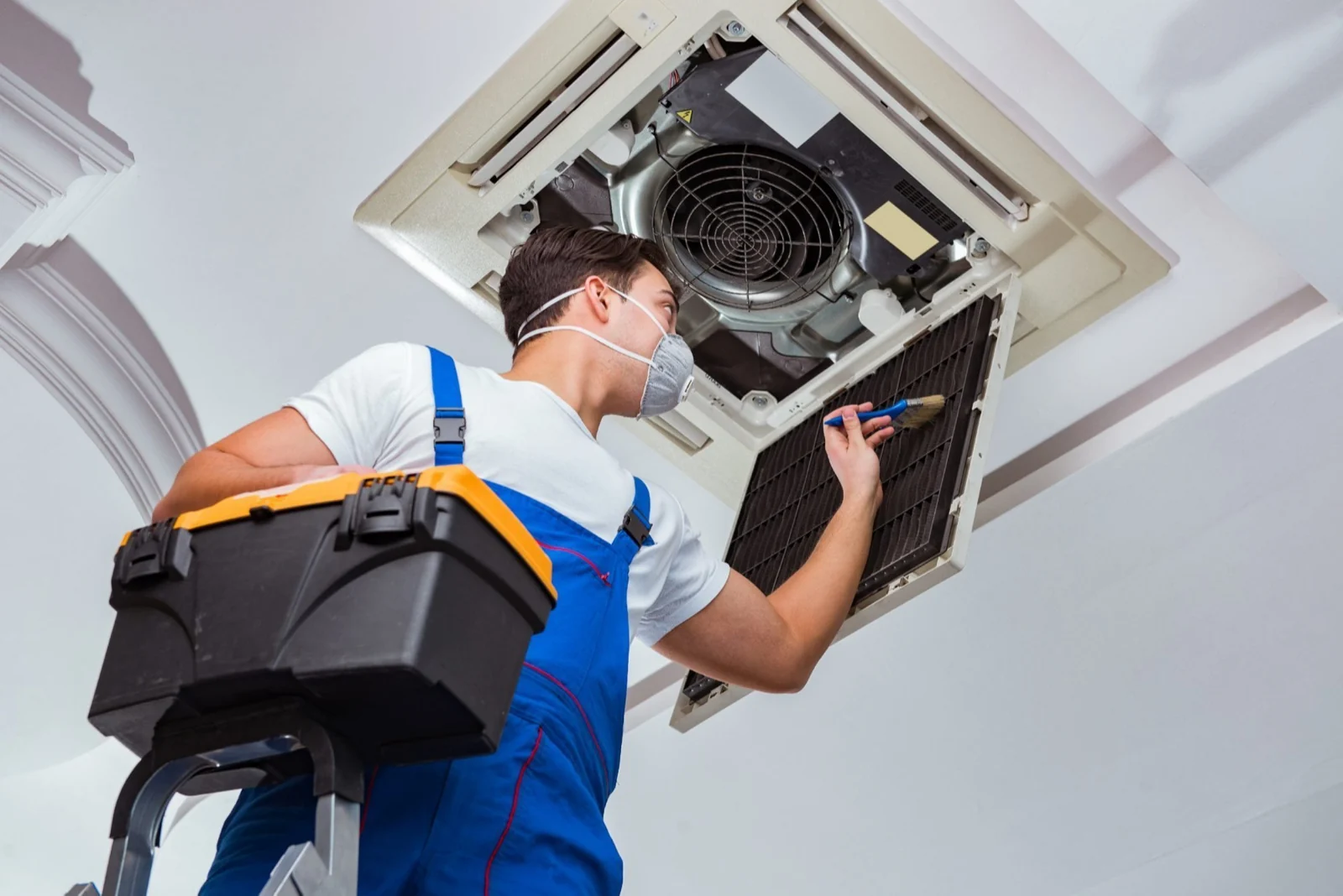 HVAC technician inspecting and cleaning a ceiling-mounted air-conditioning filter