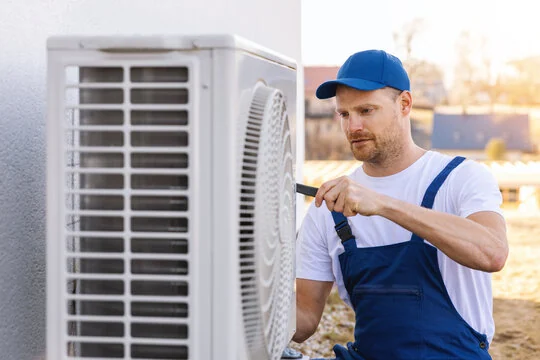 Technician servicing an outdoor heat-pump condenser